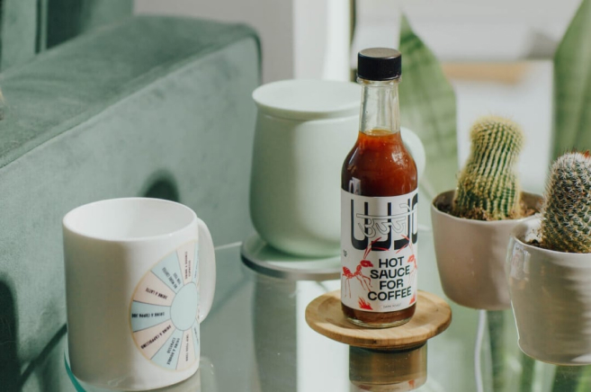 Bottle of Ujjo sauce standing on the table and surrounded by cups and cactuses in pots